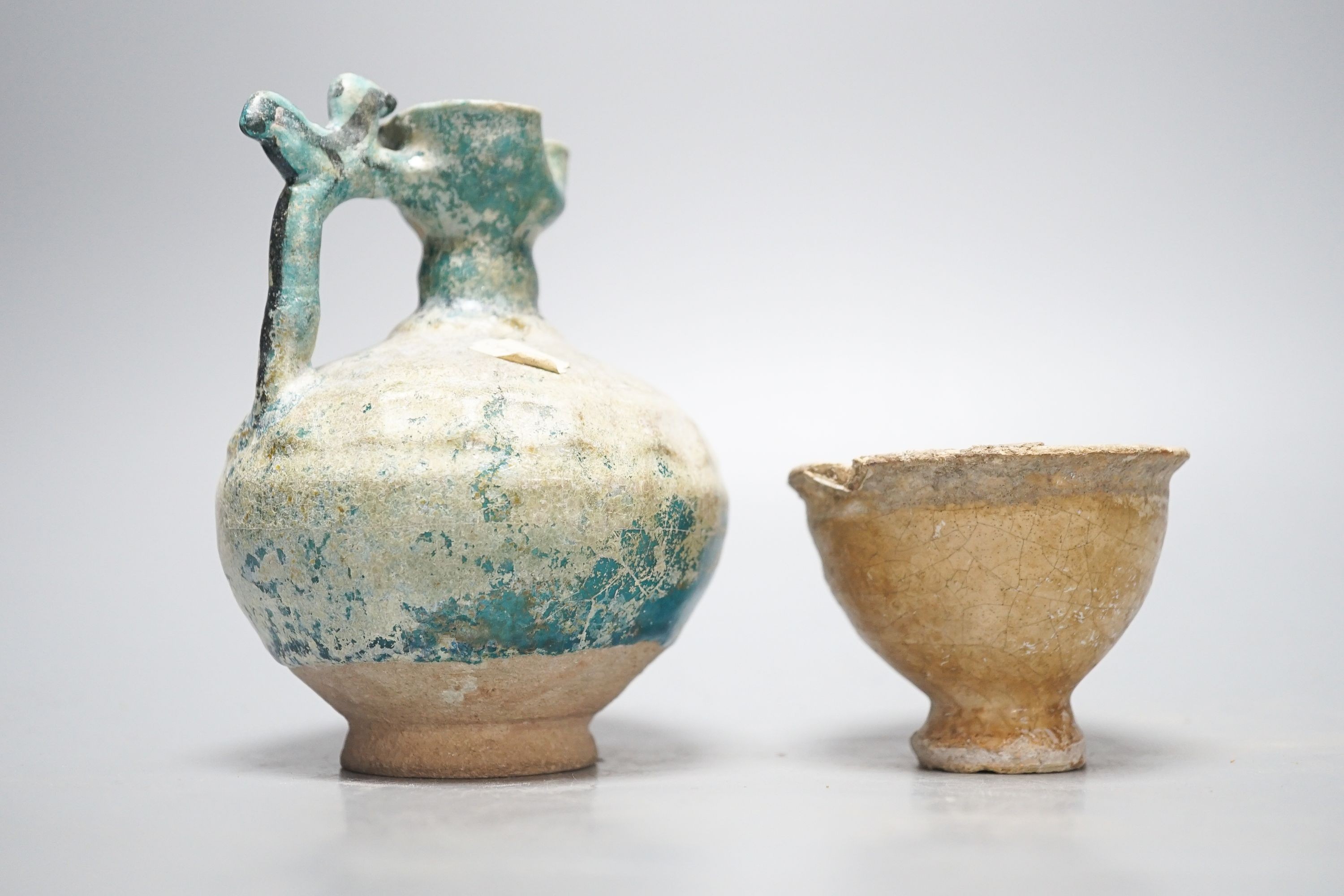 A Kashan turquoise glazed pottery ewer, 14th century, with mineral iridescence and an early Islamic pottery cup 14cm